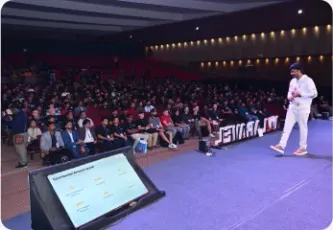 Vishal Rajpurohit speaking to a packed auditorium from a lit stage