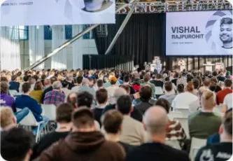 A conference screen displaying Vishal Rajpurohit's name to a seated crowd