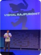 Vishal Rajpurohit on stage under a screen displaying his name